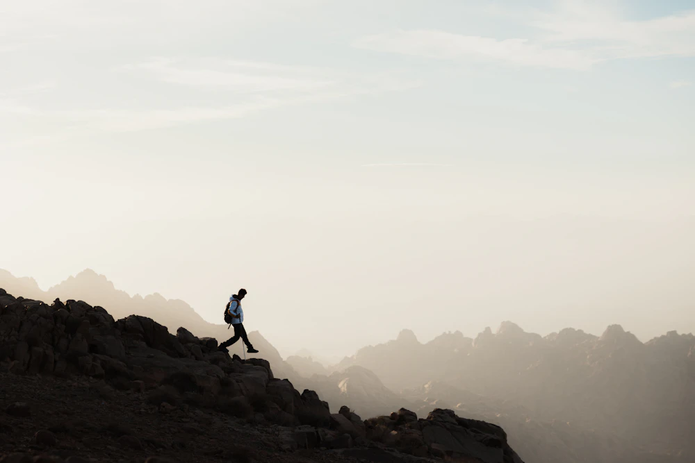 Hiker moving across a high mountain ridge in morning light